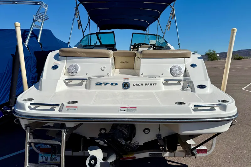 Slide: The Image of 2011 Sea Ray 270 SLX boat with swim platform and seating, parked outdoors. - 2