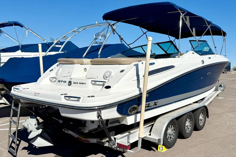 Slide: The Image of 2011 Sea Ray 270 SLX boat with blue canopy on trailer in parking lot. - 3