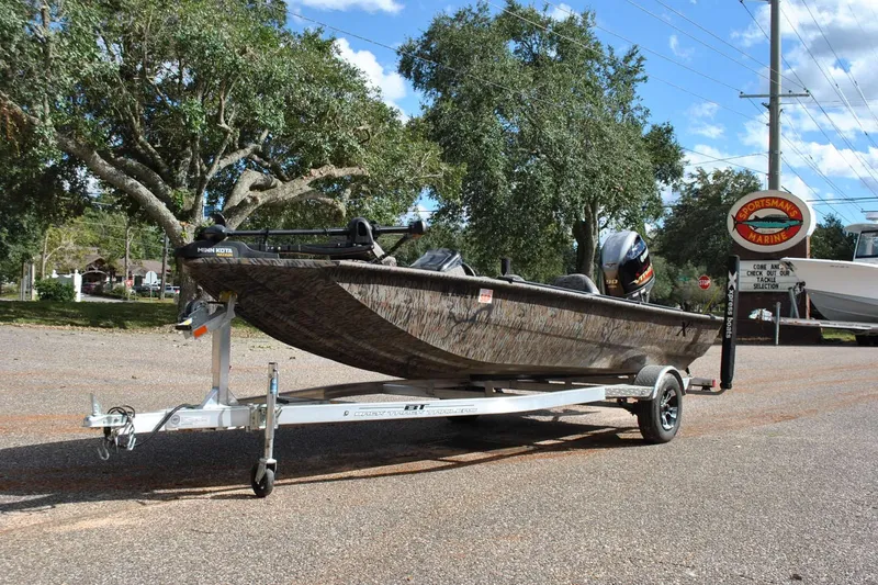 Slide: The Image of 2024 Express 180XP boat on trailer, parked outdoors near trees and a marine store. - 28