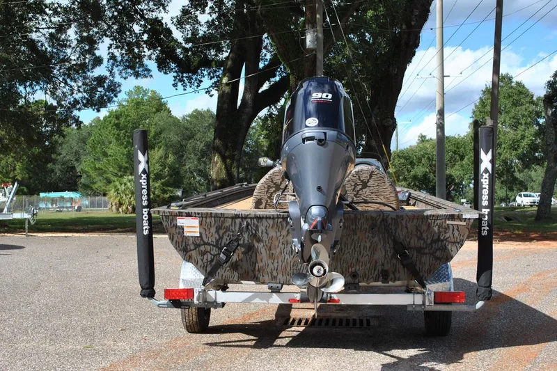 Slide: The Image of 2024 Express 180XP boat on trailer, camo design, outboard motor, parked outdoors. - 9