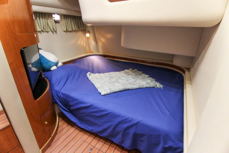 Slide: The Image of Cozy cabin interior of 2000 Sea Ray 450 Express Bridge with blue bedding and wooden accents. - 25