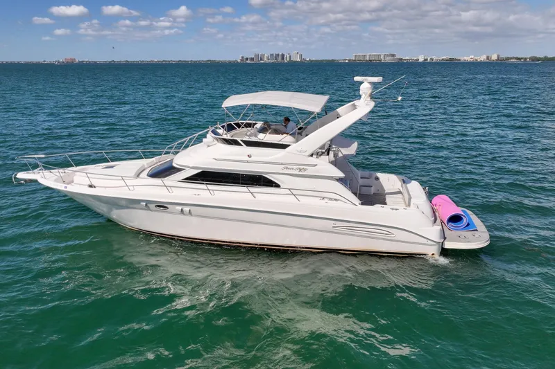 Slide: The Image of 2000 Sea Ray 450 Express Bridge cruising on blue water with city skyline backdrop. - 3