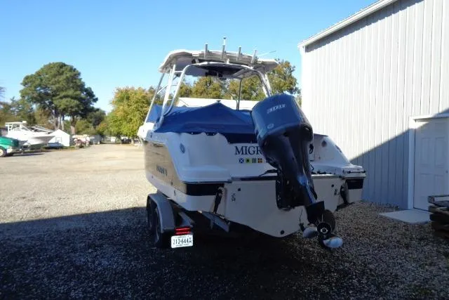 Slide: The Image of 2015 Robalo R247 Dual Console boat with outboard motor, parked outdoors near a building. - 10