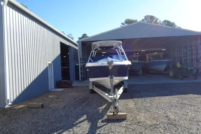 Slide: The Image of 2015 Robalo R247 Dual Console boat on trailer outside metal storage building. - 13