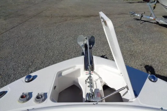 Slide: The Image of 2015 Robalo R247 Dual Console boat anchor compartment with open hatch on gravel surface. - 19