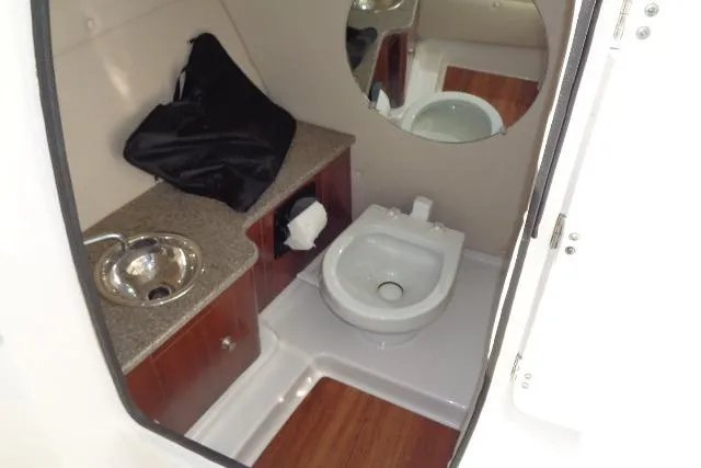 Slide: The Image of 2015 Robalo R247 Dual Console boat bathroom with sink, toilet, and wooden cabinetry. - 30