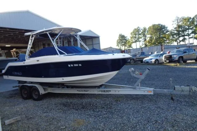 Slide: The Image of 2015 Robalo R247 Dual Console boat on trailer, parked outdoors near a warehouse. - 4