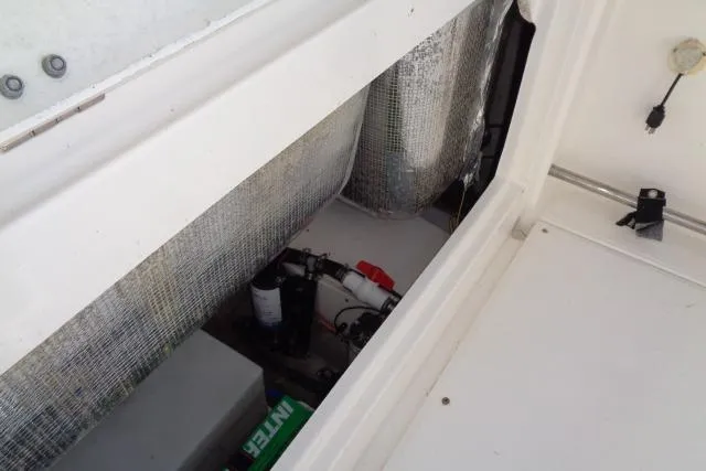 Slide: The Image of 2015 Robalo R247 Dual Console boat storage compartment with visible equipment and wiring. - 42