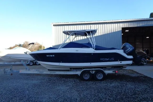 Slide: The Image of 2015 Robalo R247 Dual Console boat on trailer near a metal building. - 5