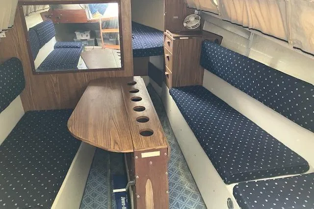 Slide: The Image of 1979 Chrysler 26 sailboat interior with blue cushioned seating and wooden table. - 22