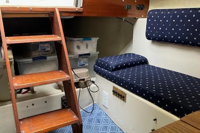 Slide: The Image of Interior of a 1979 Chrysler 26 sailboat with wooden steps and blue patterned seating. - 24