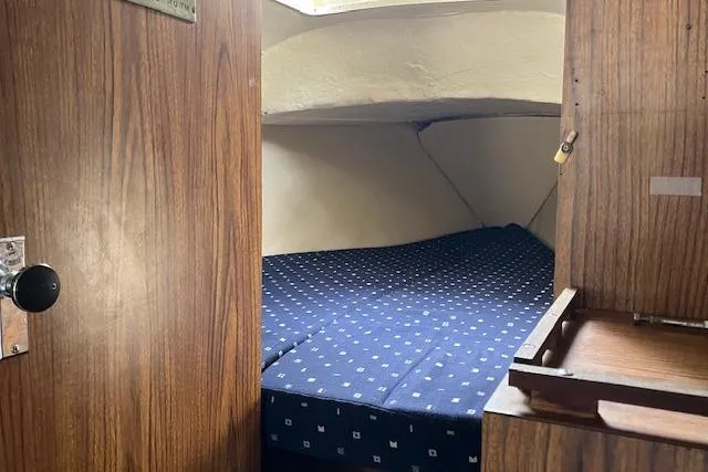 Slide: The Image of 1979 Chrysler 26 boat interior with cozy cabin bed and wooden paneling. - 26