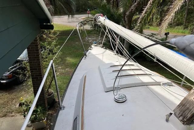 Slide: The Image of 1979 Chrysler 26 sailboat deck with mast, surrounded by greenery and a parked car. - 8