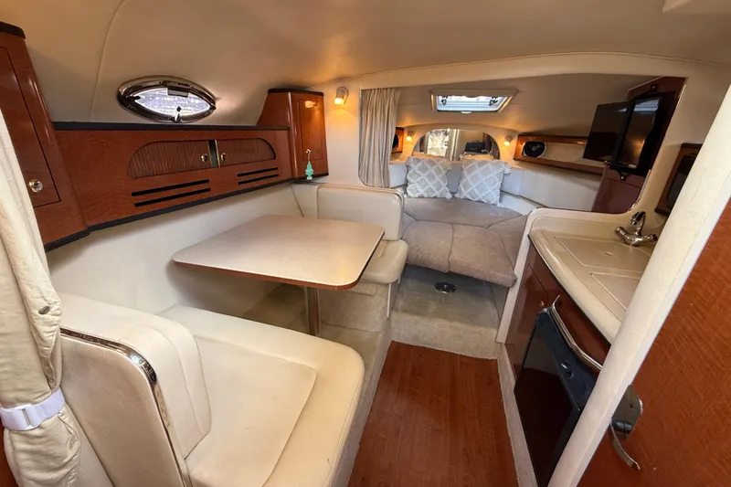 Slide: The Image of Interior of 2004 Sea Ray 280 Sundancer, featuring cozy seating and compact kitchenette. - 10