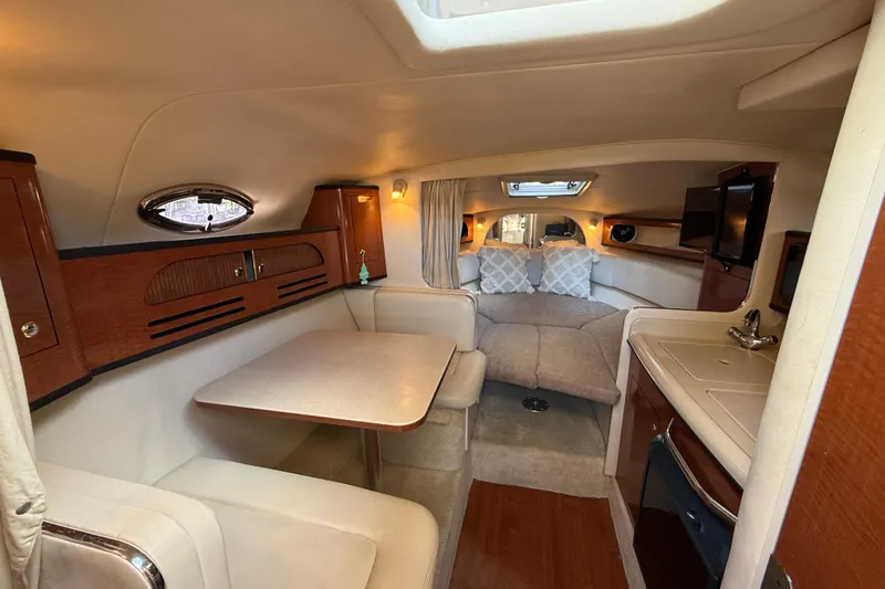 Slide: The Image of 2004 Sea Ray 280 Sundancer cabin interior with dining area, kitchenette, and cozy sleeping space. - 11