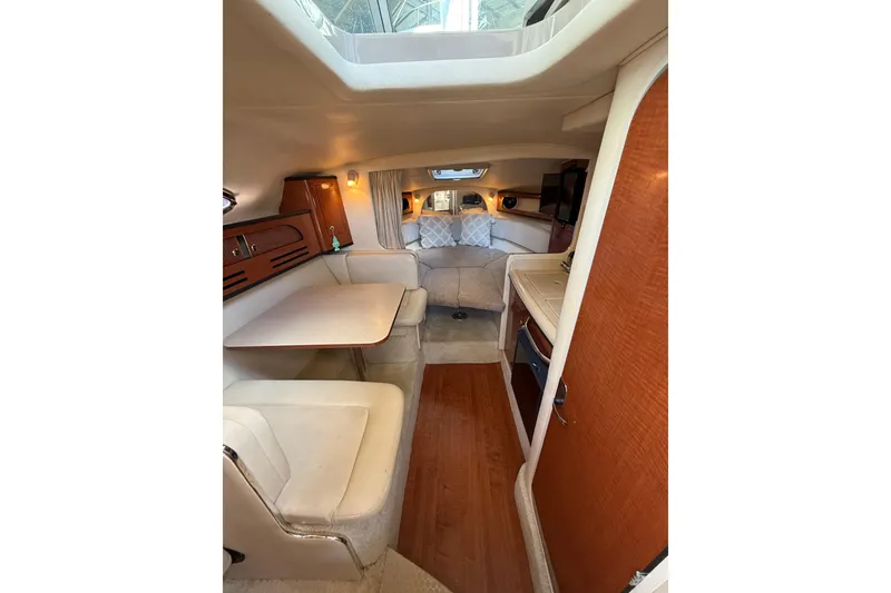 Slide: The Image of 2004 Sea Ray 280 Sundancer cabin interior with dining area and cozy seating. - 12