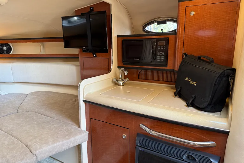 Slide: The Image of Interior of 2004 Sea Ray 280 Sundancer with kitchenette, TV, and seating area. - 14