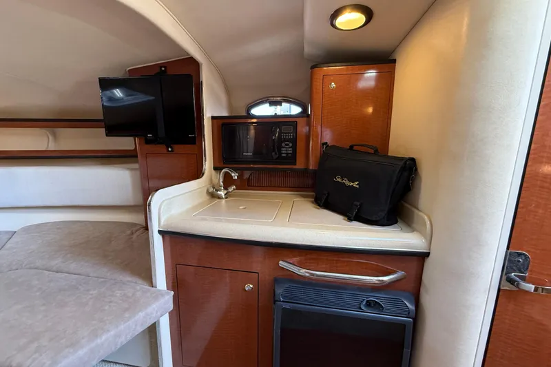 Slide: The Image of 2004 Sea Ray 280 Sundancer cabin interior with kitchenette, TV, and storage. - 15