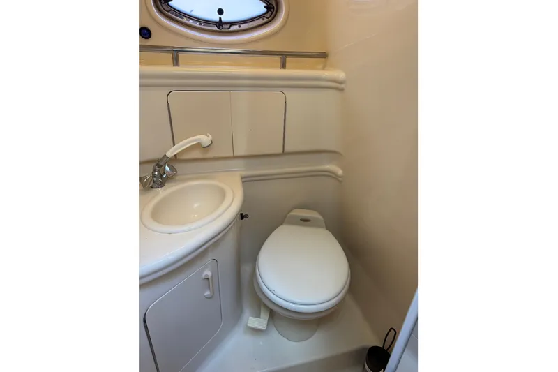Slide: The Image of 2004 Sea Ray 280 Sundancer bathroom with sink, toilet, and porthole window. - 18
