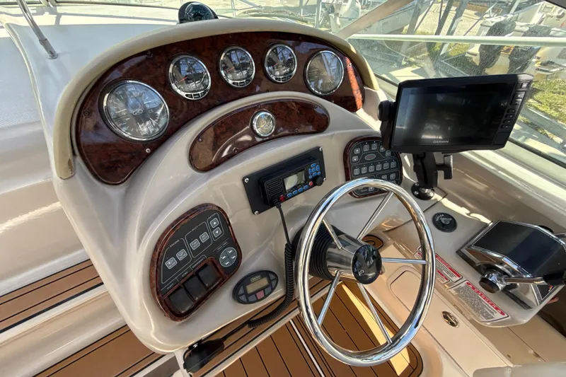 Slide: The Image of 2004 Sea Ray 280 Sundancer helm with gauges, steering wheel, and navigation equipment. - 7