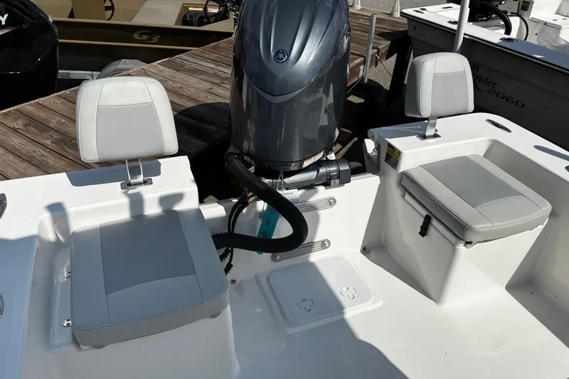 Slide: The Image of 2026 Bay Rider 2260 boat interior with seating and motor, docked on wooden pier. - 13