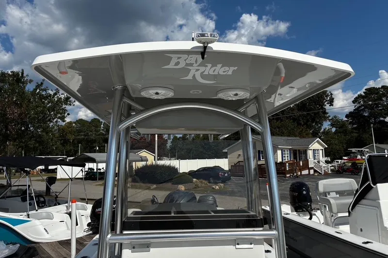 Slide: The Image of 2026 Bay Rider 2260 boat with T-top, parked outdoors under a partly cloudy sky. - 16