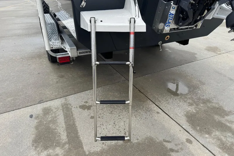 Slide: The Image of Bay Rider 2260 FS 2026 boat ladder on trailer, parked on wet pavement. - 12