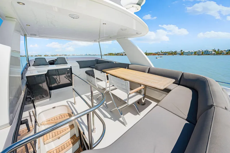 Slide: The Image of Luxurious 2017 Princess 56 yacht deck with seating and table, overlooking serene waters. - 48