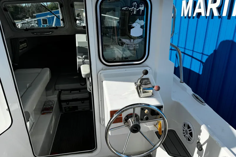 Slide: The Image of 2021 Parker 2320 Sport Cabin boat interior with steering wheel and cabin view. - 34
