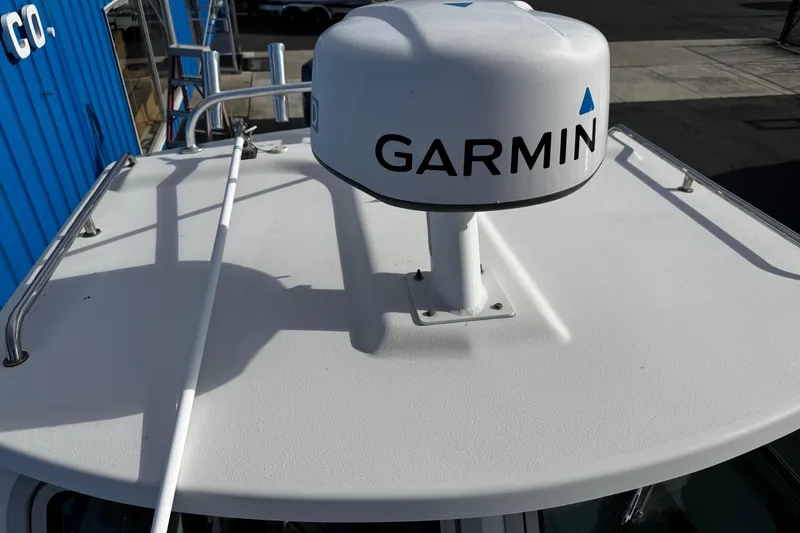 Slide: The Image of Parker 2320 Sport Cabin 2021 with Garmin radar on roof, docked near blue building. - 8