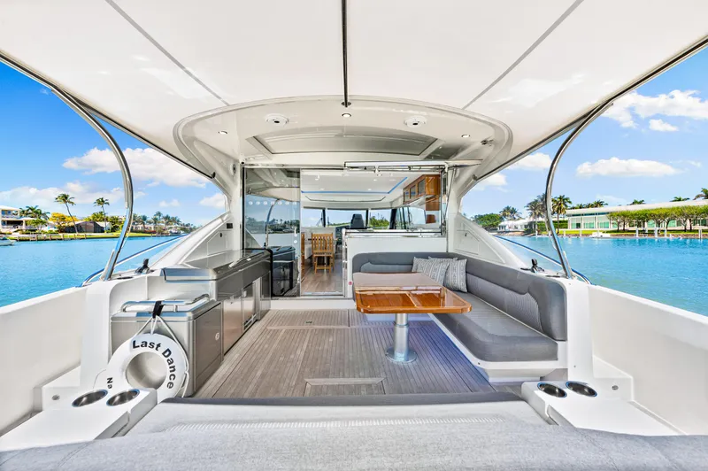 Slide: The Image of 2022 Riviera 5400 Sport Yacht interior with seating and table, overlooking serene water and blue sky. - 37