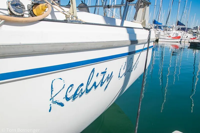 Slide: The Image of 1984 Catalina 36 sailboat docked in marina, featuring "Reality Check" name on hull. - 2