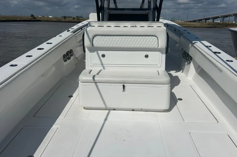 Slide: The Image of 2016 SeaHunter 39 Tournament boat interior with white seating and storage, on calm water. - 8