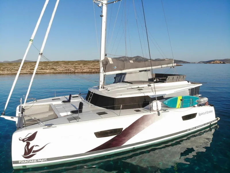 Slide: The Image of 2023 Fountaine Pajot Tanna 47 catamaran, "Spirit of Ecstasy," docked in a marina. - 1