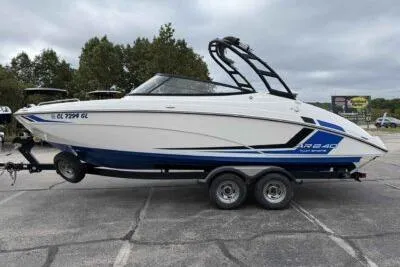 Slide: The Image of 2018 Yamaha Boats AR240 on trailer, white and blue design, parked outdoors. - 4