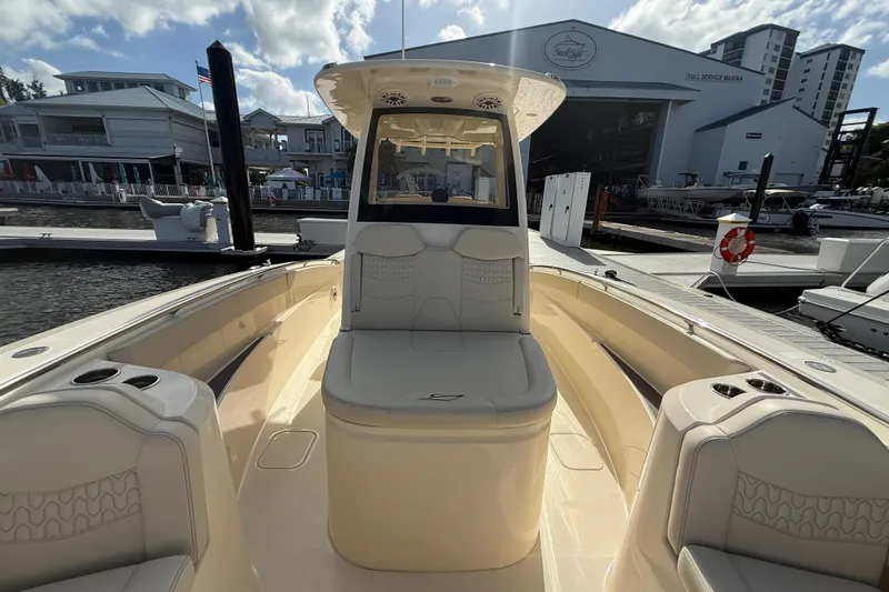 Slide: The Image of 2026 Scout 288 LXF boat interior at marina, showcasing seating and helm. - 14