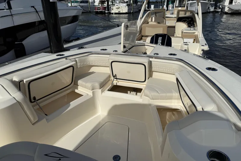 Slide: The Image of 2026 Scout 288 LXF boat interior with seating and storage at a marina. - 18