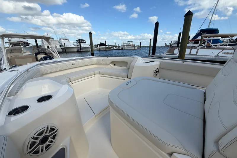 Slide: The Image of 2026 Scout 288 LXF boat interior with seating, docked at marina under blue sky. - 20