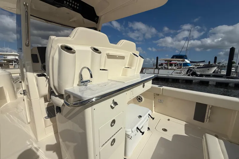 Slide: The Image of 2026 Scout 288 LXF boat interior with seating, sink, and storage at marina. - 6