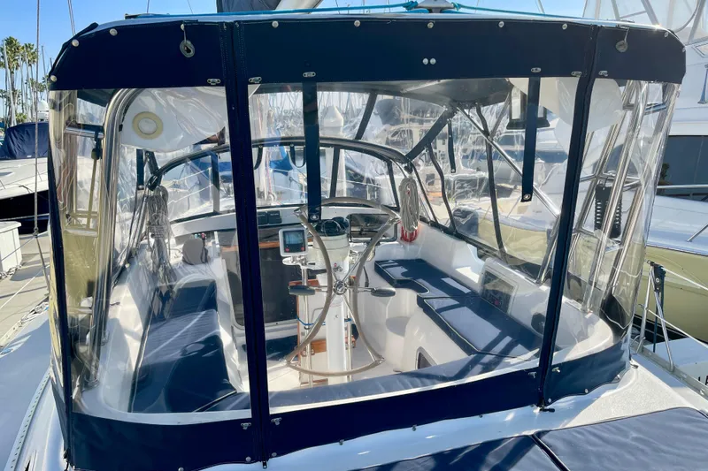 Slide: The Image of 1998 Hunter Passage 42 sailboat cockpit with clear enclosure and steering wheel. - 10