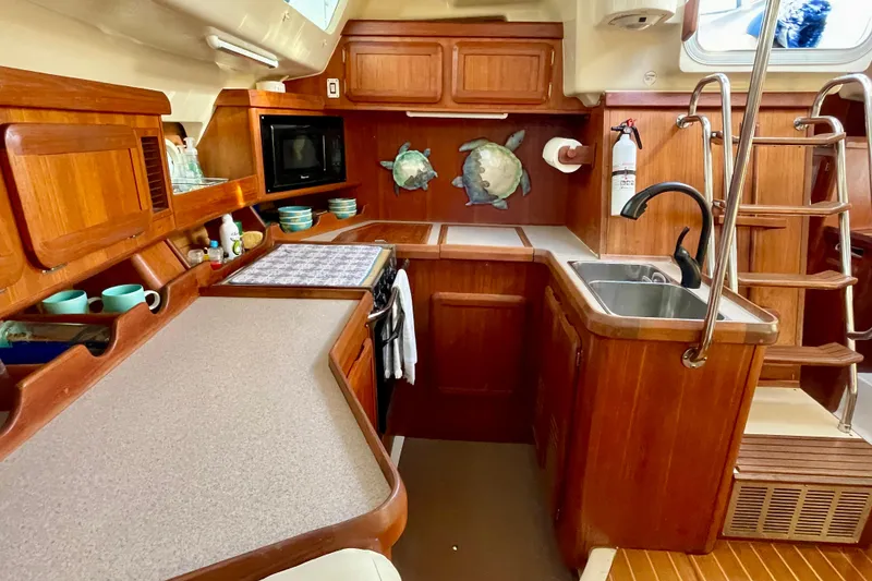 Slide: The Image of 1998 Hunter Passage 42 yacht kitchen with wooden cabinetry and modern amenities. - 38