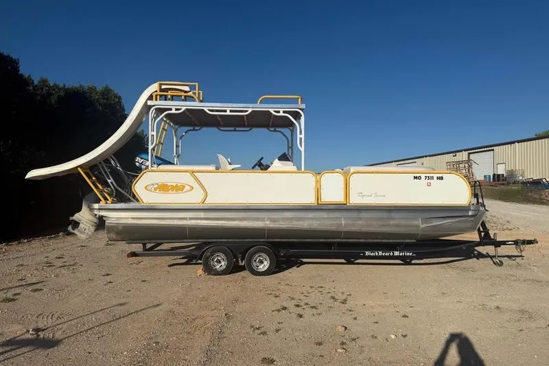 Slide: The Image of 2022 Aloha Pontoon Tropical 260 with slide, parked on a trailer under clear blue sky. - 0