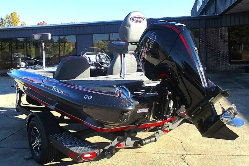 Slide: The Image of 2026 Triton 179 TrX boat interior with red and gray seating, steering wheel, and deck. - 5