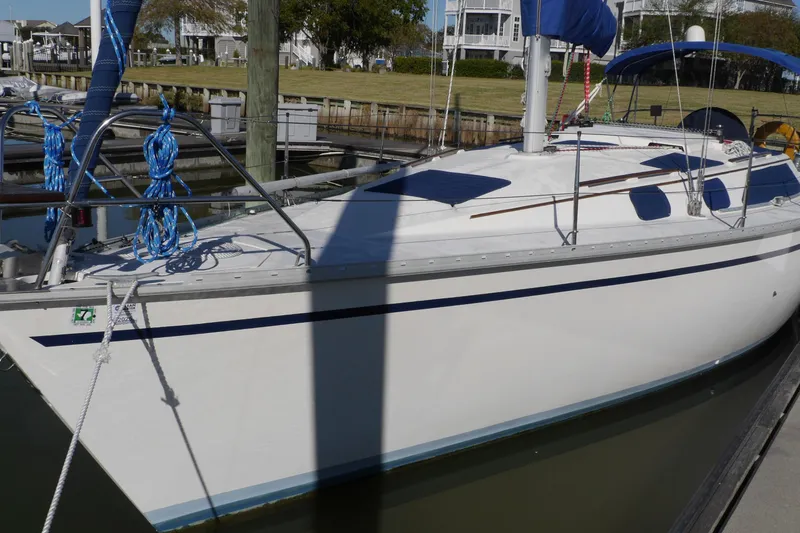Slide: The Image of 1990 Hunter Legend 35.5 sailboat docked in marina, featuring blue accents and rigging. - 2