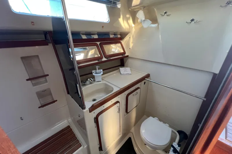 Slide: The Image of 1990 Hunter Legend 35.5 yacht bathroom with sink, toilet, and wooden accents. - 32
