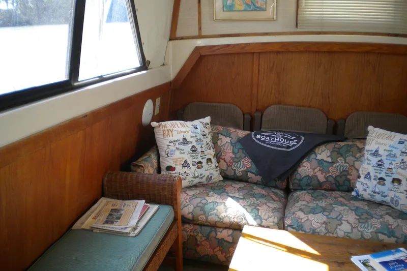 Slide: The Image of 1988 Mainship 40 Double Cabin interior with floral sofa, nautical pillows, and wooden accents. - 13