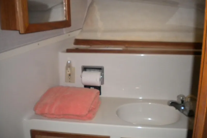 Slide: The Image of 1988 Mainship 40 Double Cabin bathroom with sink, mirror, and pink towel. - 15