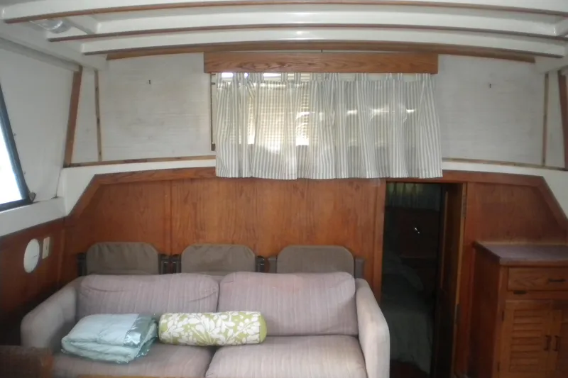 Slide: The Image of 1988 Mainship 40 Double Cabin interior with sofa, wooden paneling, and striped curtains. - 27