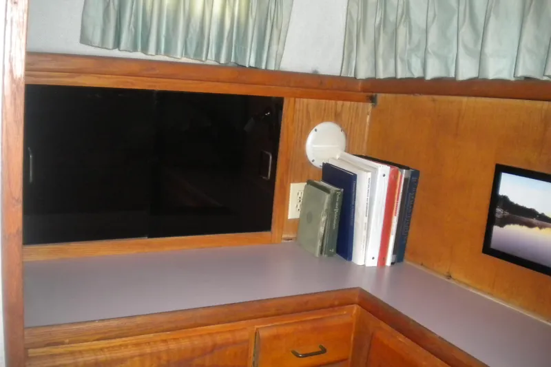 Slide: The Image of 1988 Mainship 40 Double Cabin interior with books, wooden cabinetry, and a small framed picture. - 31