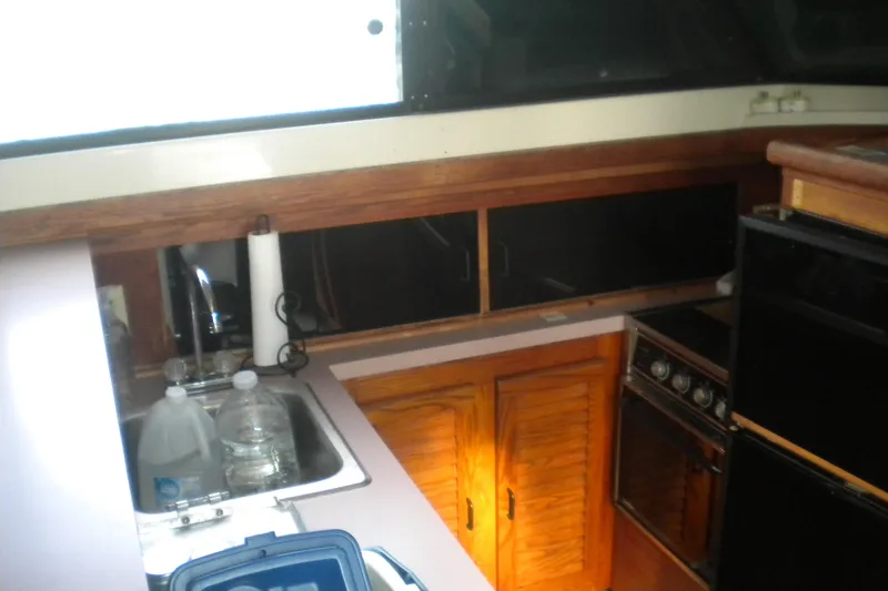 Slide: The Image of 1988 Mainship 40 Double Cabin kitchen with sink, stove, and wooden cabinets. - 40